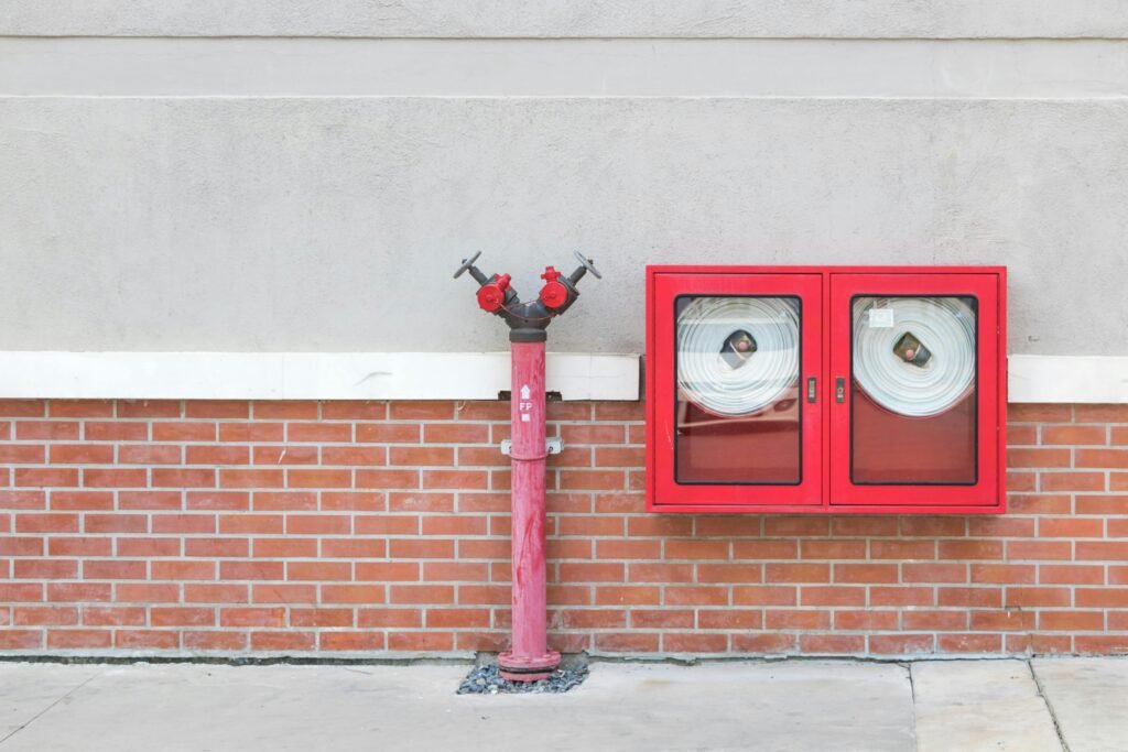 Outdoor fire hydrant and hoses against a brick wall, emphasizing fire safety.